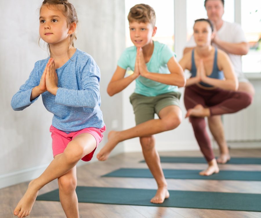 Family with two children doing yoga on mats in fitness studio